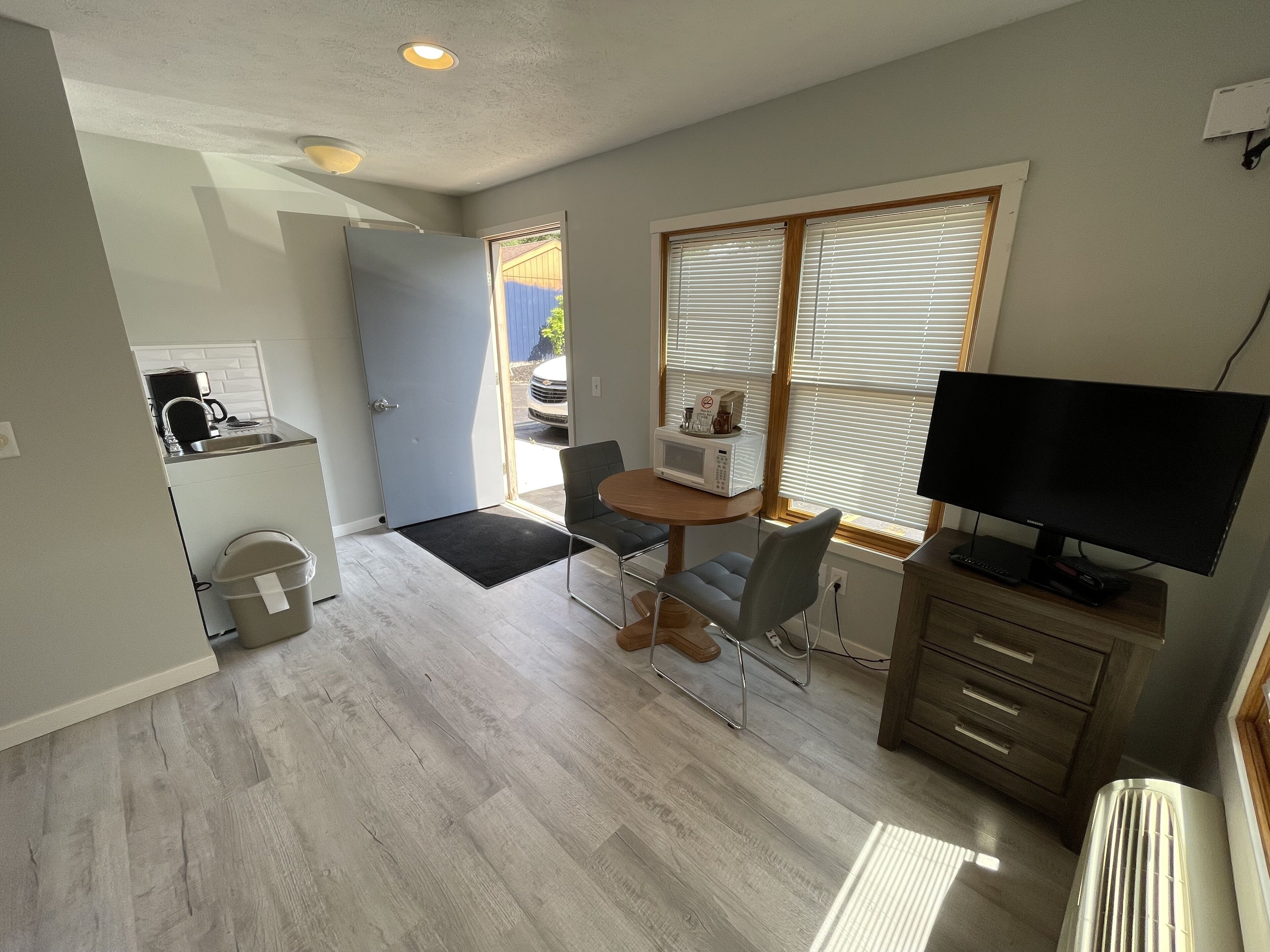 A compact living space with a kitchenette, dining area, and a television.