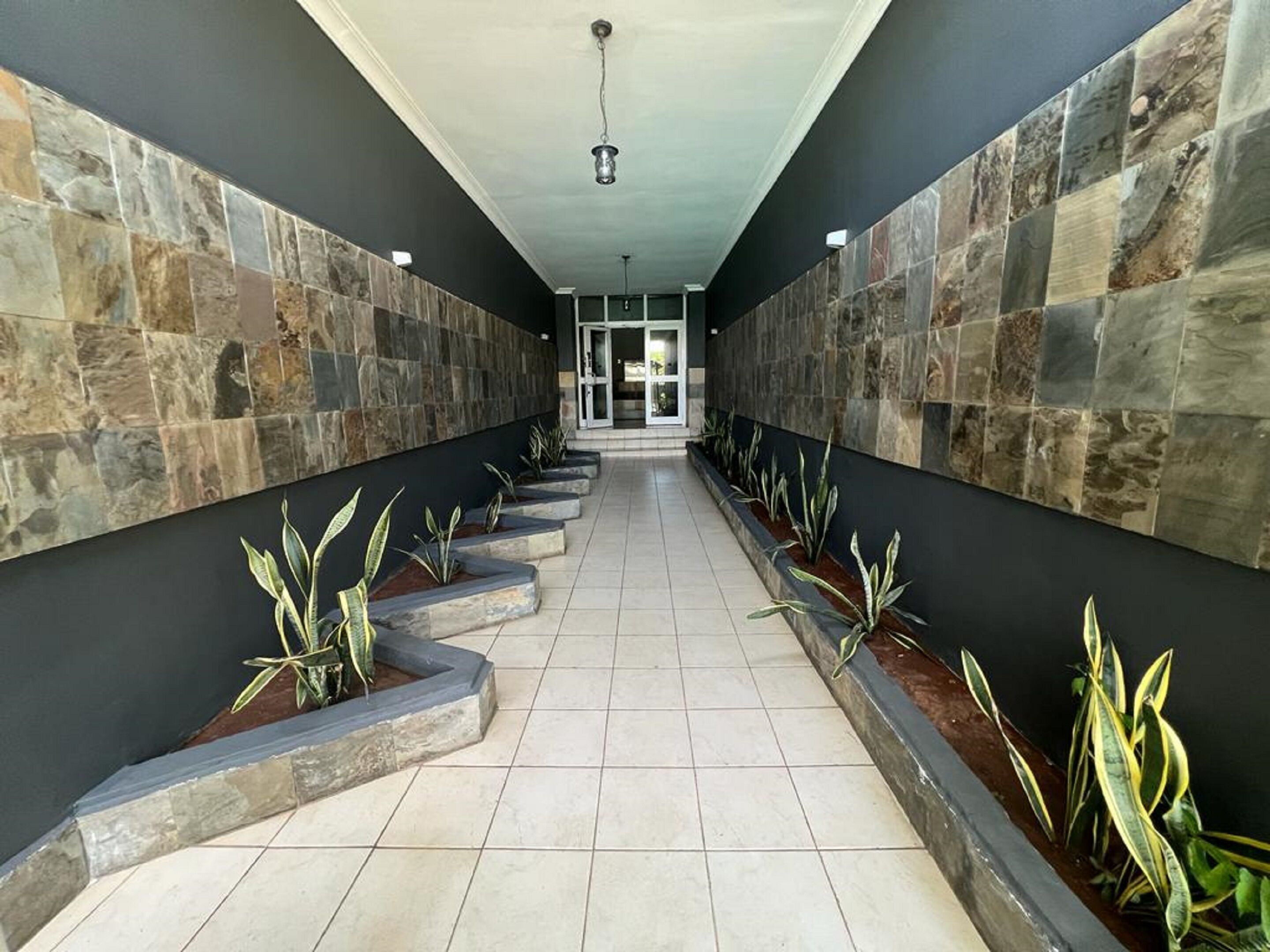 A corridor with stone walls and planters with green plants.