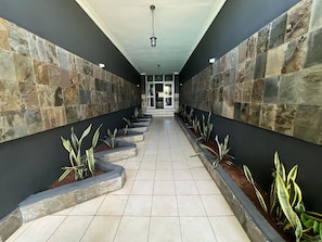 Un pasillo con paredes de piedra y macetas con plantas verdes.