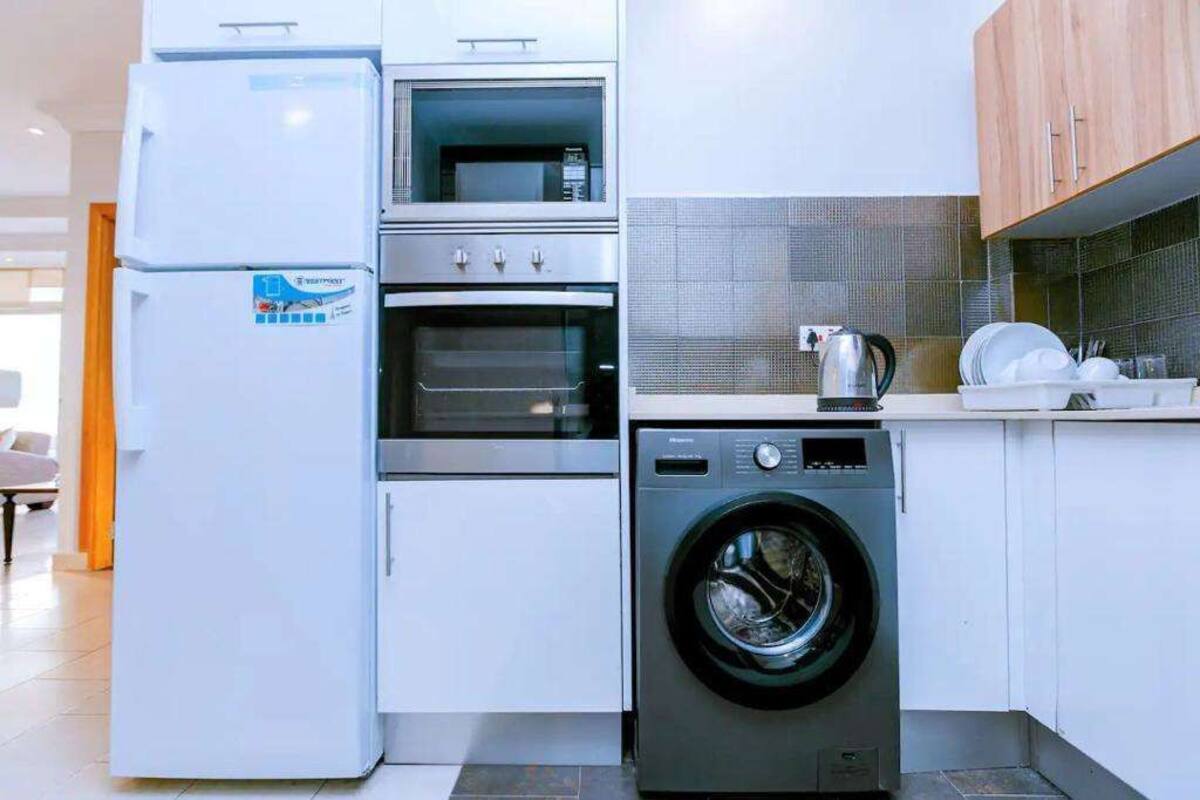 Une cuisine compacte équipée d’un four encastré, d’un four à micro-ondes et d’un lave-linge à chargement frontal.