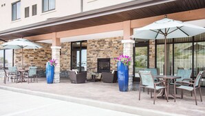 An outdoor patio with stone walls, a fireplace, and outdoor seating with umbrellas.