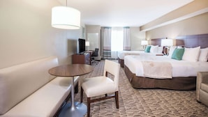 A hotel room with a large bed, a desk, a chair, and a sofa.
