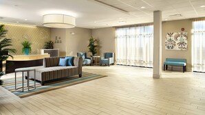 A spacious lobby with a reception desk, seating area, and large windows.