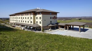 A multi-story hotel with a flat roof, outdoor seating area, and a covered patio.