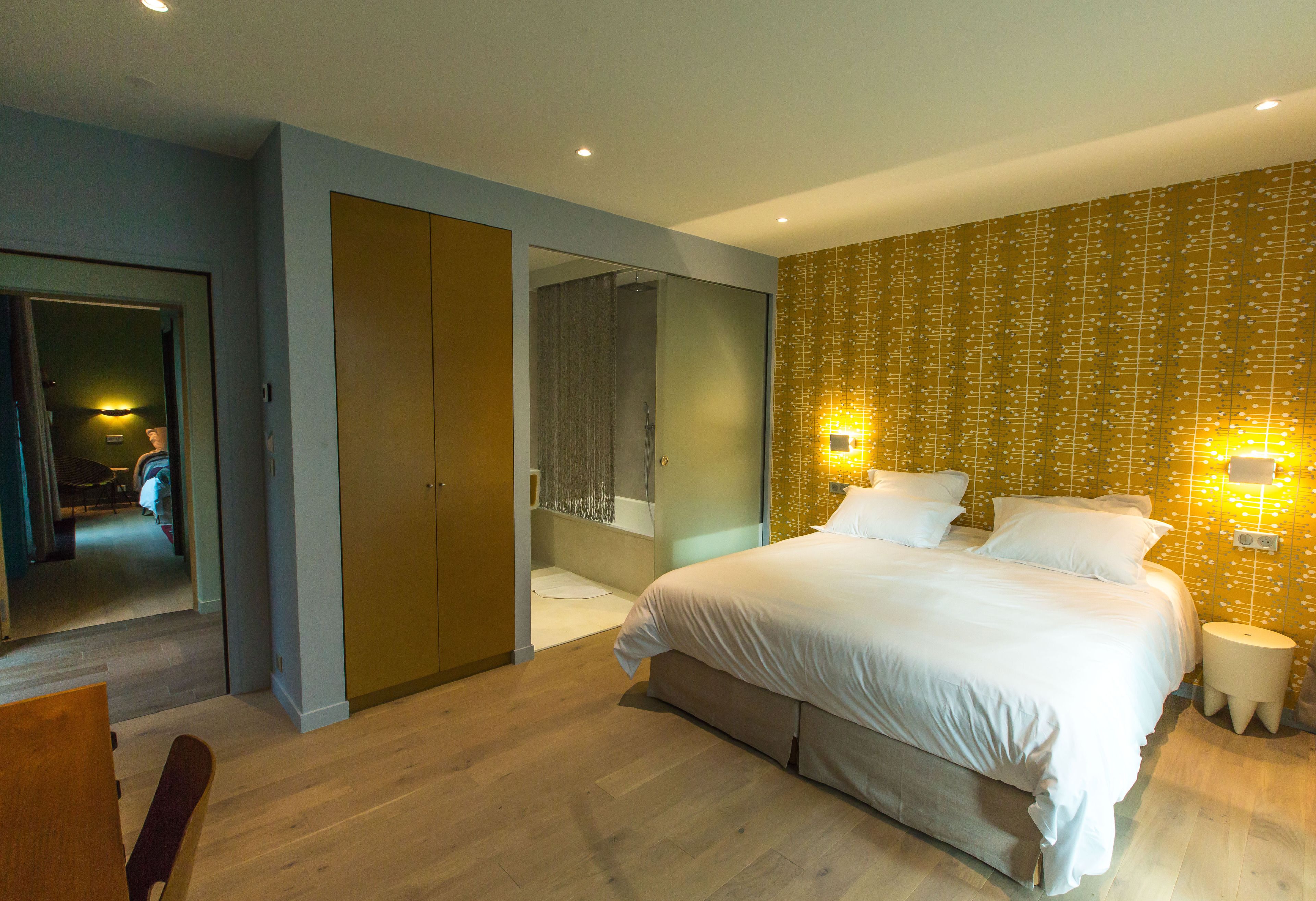 A modern bedroom with a large bed, a walk-in closet, and a bathroom with a glass shower.
