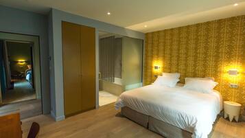 A modern bedroom with a large bed, a walk-in closet, and a bathroom with a glass shower.