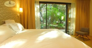 A hotel room with a large bed, a chair, a window with curtains, and a wall-mounted lamp. - Eden Lodge Paris (Paris)