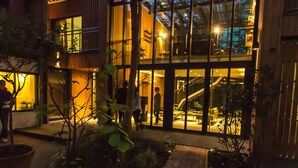Un edificio moderno con amplios ventanales, un sendero de ladrillo y plantas en macetas.