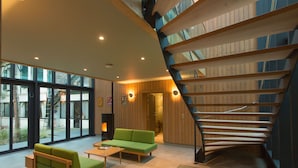 Un interior moderno con una escalera en espiral, sofás verdes y una mesa de centro de cristal.
