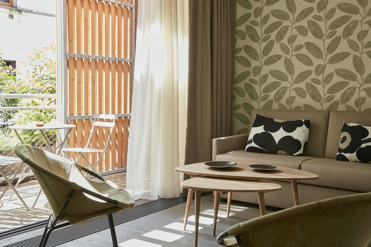 A modern living room with a sofa, two side tables, and a garden chair.