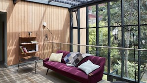 Una habitación moderna con pared de madera, un sofá morado, una mesita y una estantería.