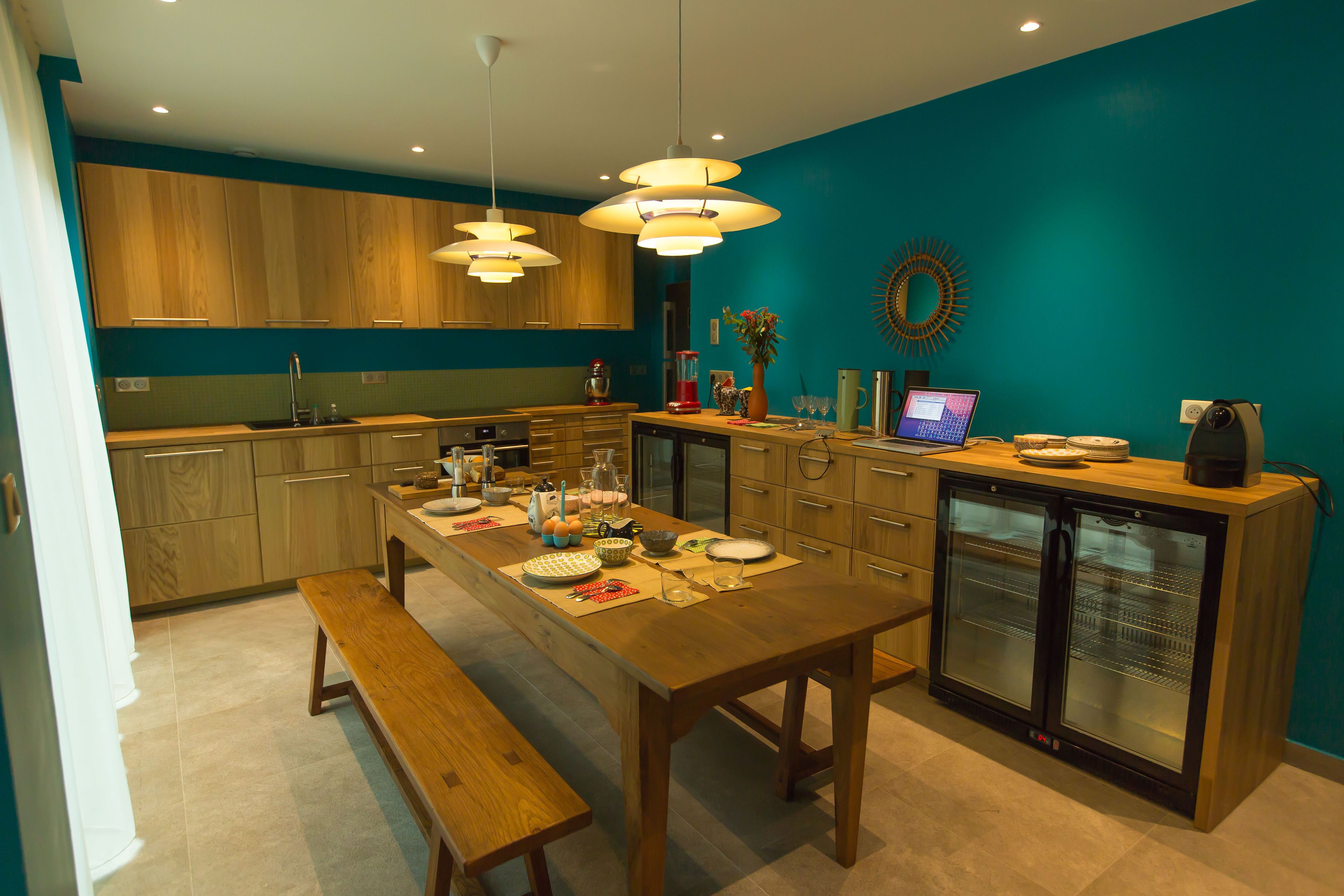 A modern kitchen with wooden cabinets, a central island, pendant lighting, and a built-in refrigerator.
