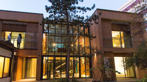 Un edificio moderno con fachada de vidrio, revestimiento de madera y una escalera que conduce a un nivel superior.