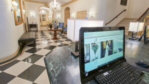 A hotel lobby with a checkered floor, a chandelier, a desk with a laptop, and a staircase. - 3 West Club (New York)