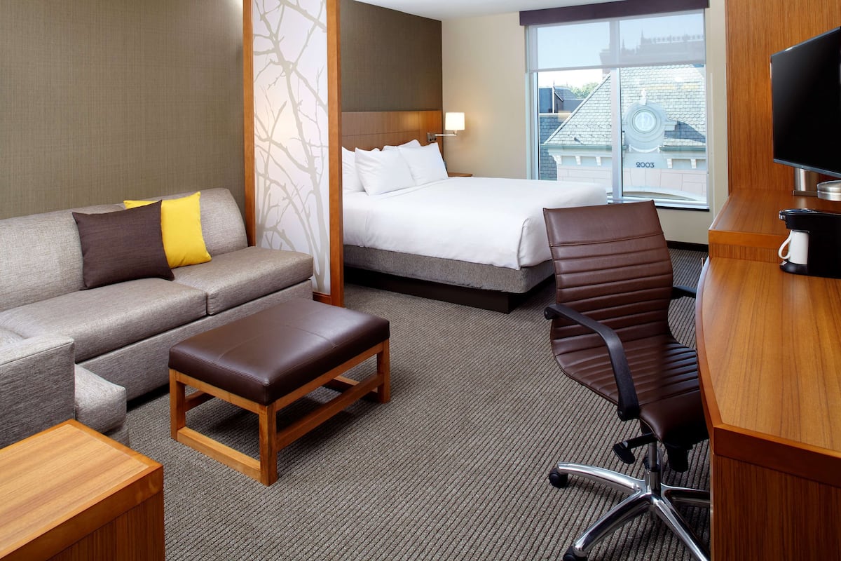 A hotel room with a bed, a sofa, a desk, and a chair.
