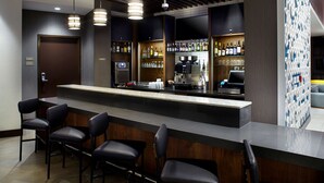 A bar area with a long counter, multiple bar stools, and a coffee machine. - Hyatt Place Cleveland/Lyndhurst/Legacy Village (Lyndhurst)