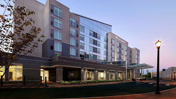A modern hotel with a glass facade, multiple floors, and a covered entrance area. - Hyatt Place Cleveland/Lyndhurst/Legacy Village (Lyndhurst)