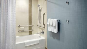 A modern bathroom with a bathtub, shower, and grab bars.