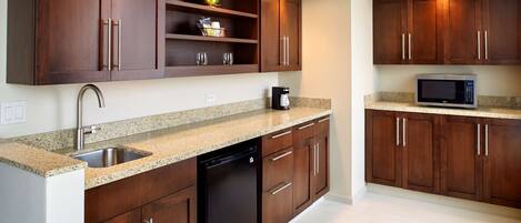 Una cocina con gabinetes de madera, un lavamanos de acero inoxidable, un lavavajillas y un microondas.
