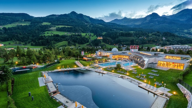 Een resort met een groot zwembad, buitenzitgedeeltes en uitzicht op de omliggende bergen.