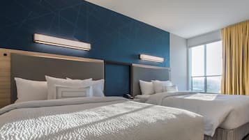 Une chambre d’hôtel avec deux lits, un design moderne et une grande fenêtre donnant sur la ville.