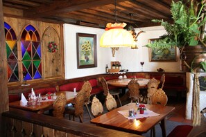 Un restaurante con muebles de madera, vidrieras y una lámpara colgante grande.