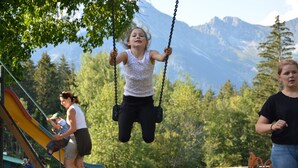 A playground with swings and a slide, surrounded by trees and mountains in the background. - Wirtshaus Nattererboden (Natters)