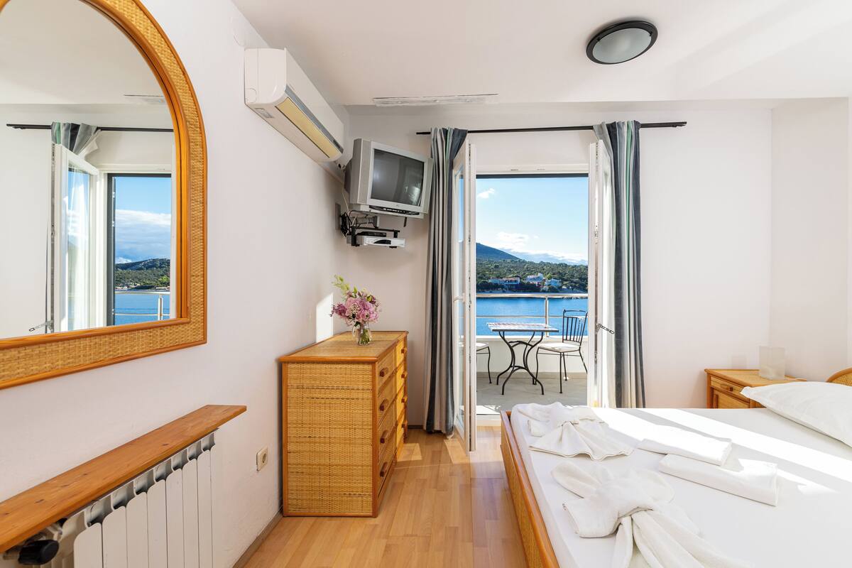 A hotel room with a bed, dresser, TV, and a balcony with a table and chairs.