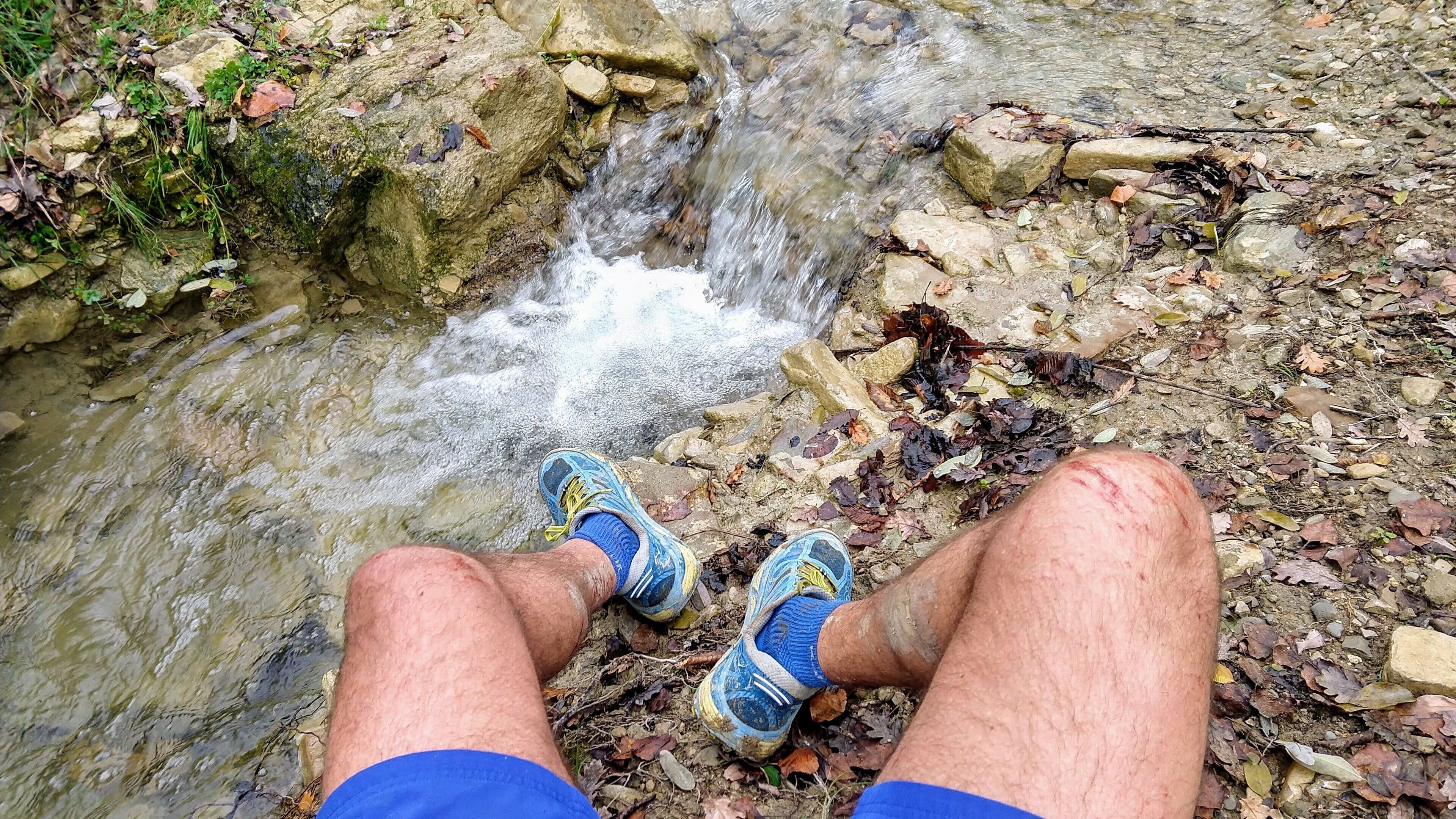 Une personne est assise au bord d’un ruisseau, l’eau s’écoulant sur les rochers.