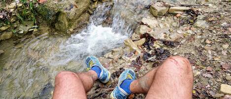 Une personne est assise au bord d’un ruisseau, l’eau s’écoulant sur les rochers.
