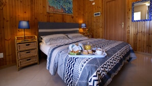 A wooden-paneled bedroom with a bed, two bedside lamps, a tray with breakfast items, and a painting on the wall. - Il Querceto - B&B e Appartamenti Vacanze (Perugia)