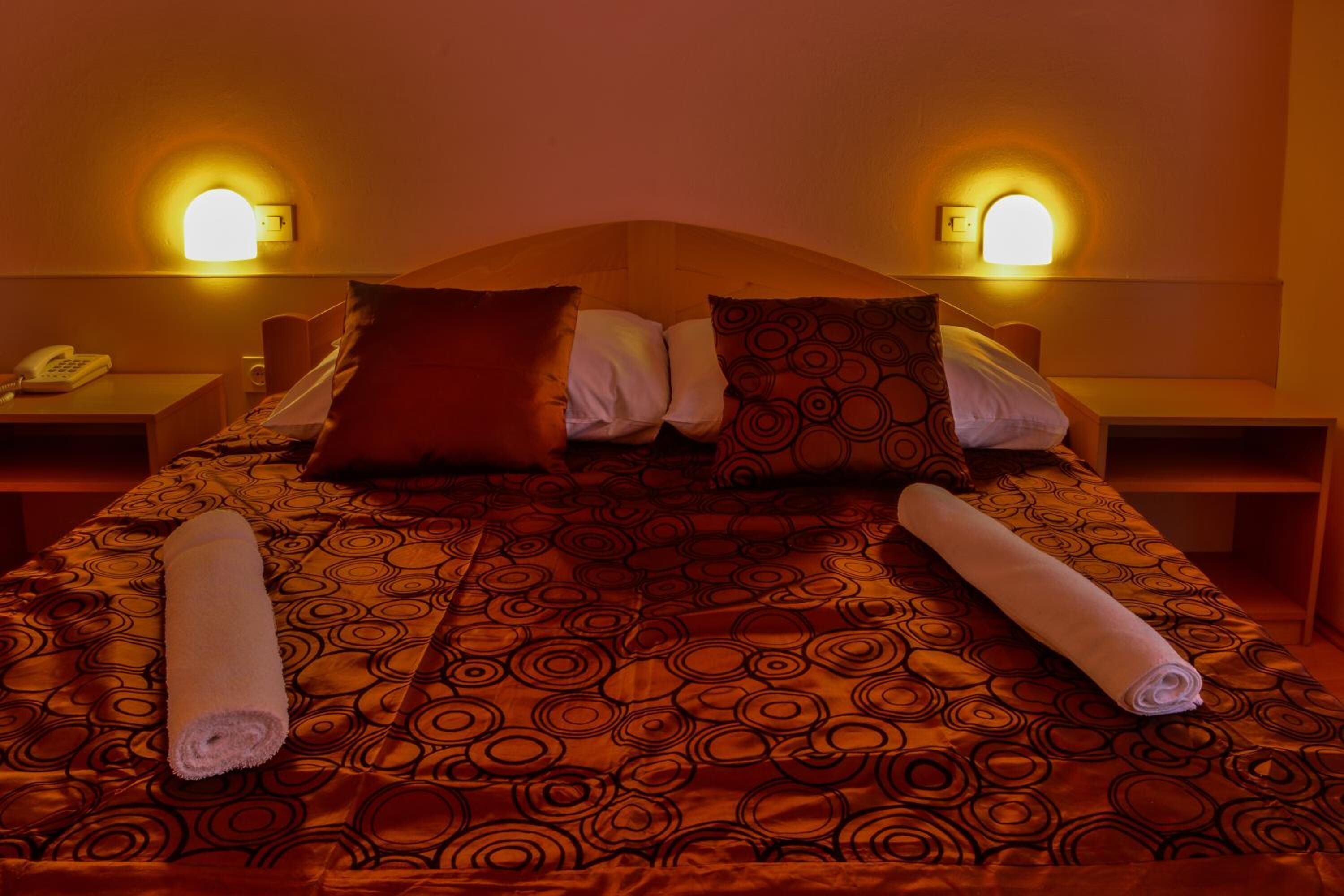 Ein Hotelzimmer mit einem Bett, zwei Nachttischen und zwei Wandlampen.