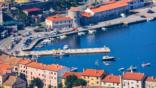 A coastal town with a historic fort, a marina with boats, and buildings with red-tiled roofs. - Hotel Art (Senj)