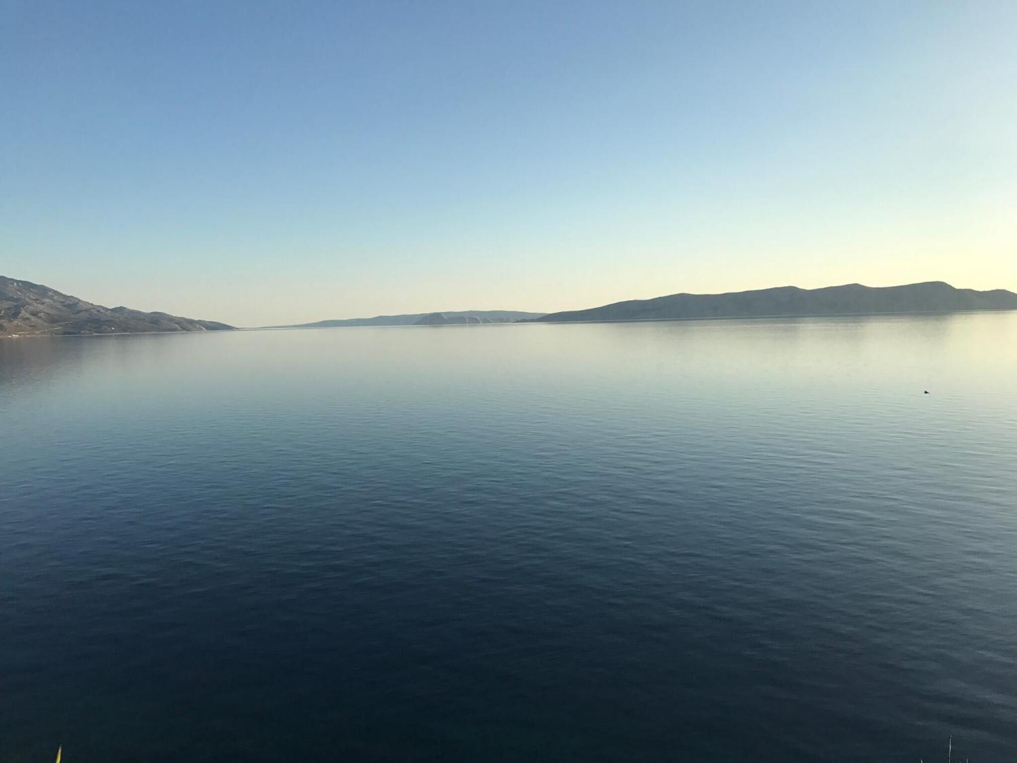 A calm lake with distant mountains and clear skies.