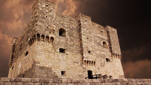 A historic stone castle with multiple towers and arched windows, set against a dramatic sky. - Hotel Art (Senj)