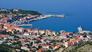 A coastal town with a marina, buildings with red roofs, and a prominent tower. - Hotel Art (Senj)