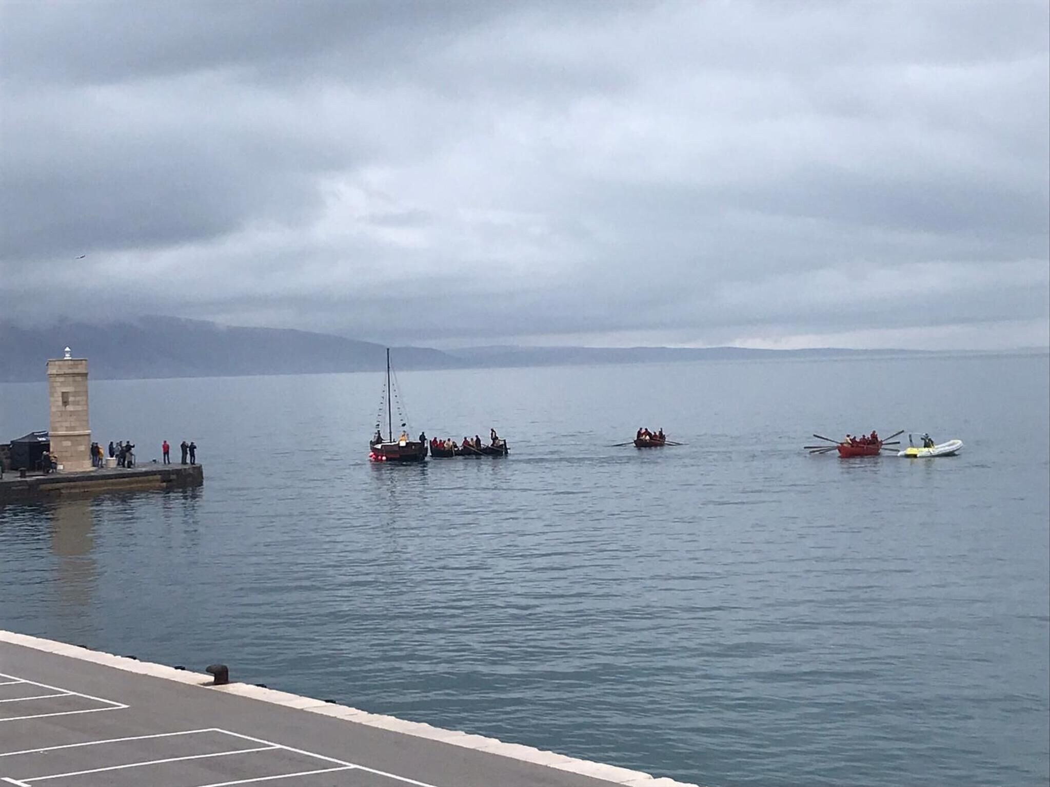 A calm body of water with boats and a lighthouse.