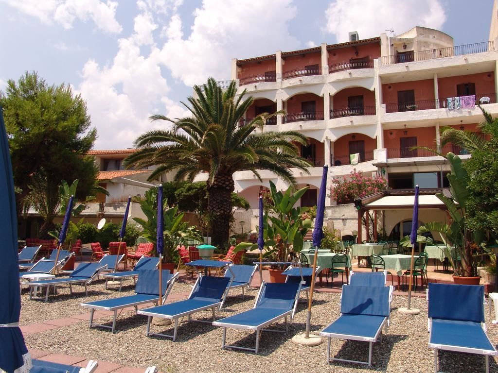 A hotel with outdoor seating areas, palm trees, and a multi-story building with balconies.