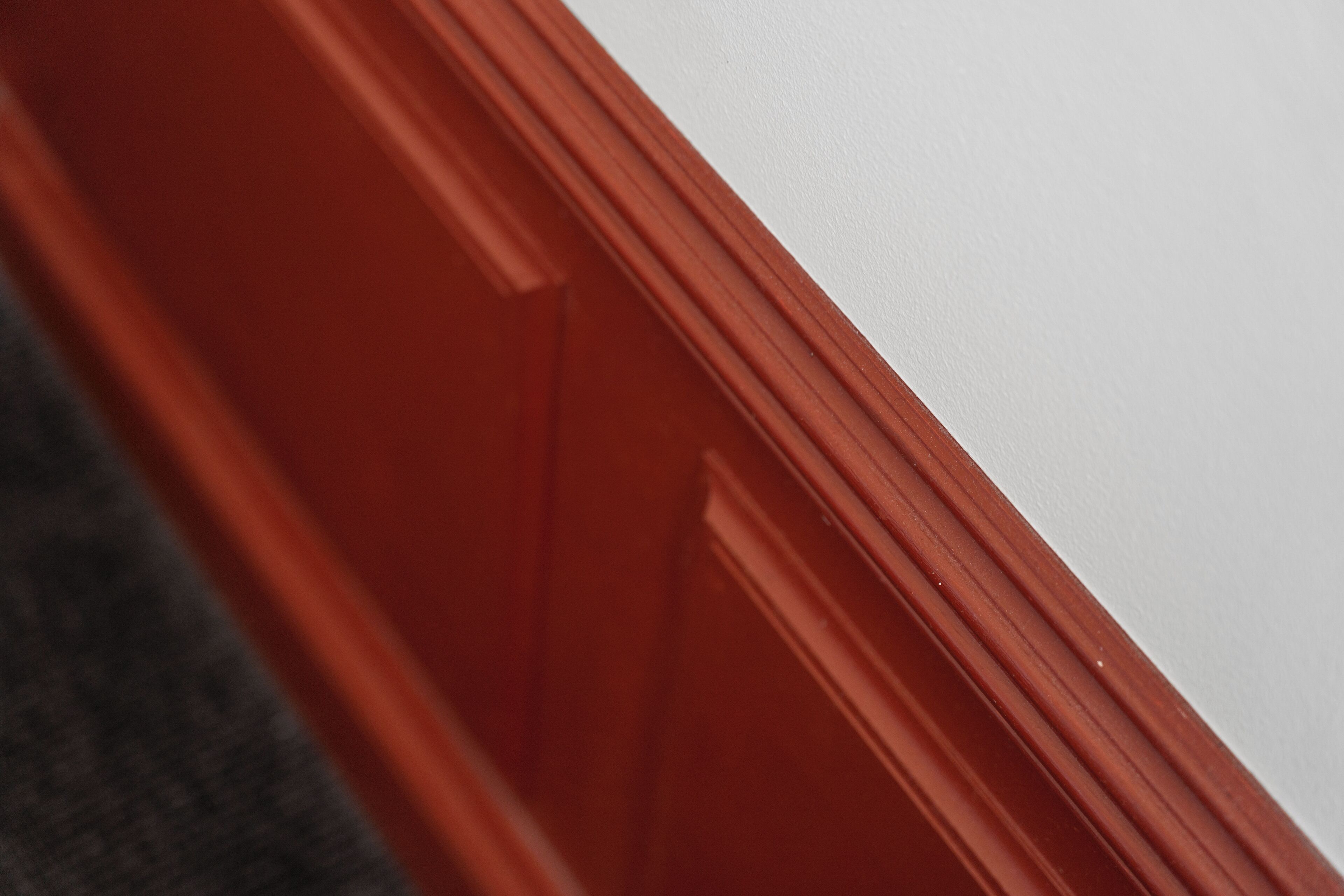 Un primer plano del marco rojo de una puerta de madera.