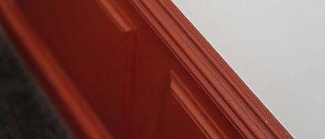 Un primer plano del marco rojo de una puerta de madera.
