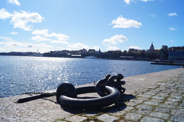 A waterfront view with a large anchor on the cobblestone path. - Hotell Skeppsbron (Stockholm)