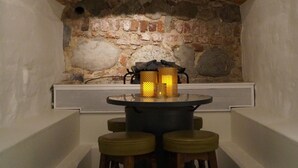 A stone-walled alcove with a brick arch, a table with stools, and a lit candle holder. - Hotell Skeppsbron (Stockholm)