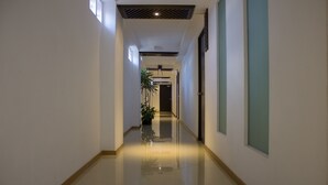 A hallway with a tiled floor, a potted plant, and a door at the end. - My Home Suites (Celaya)