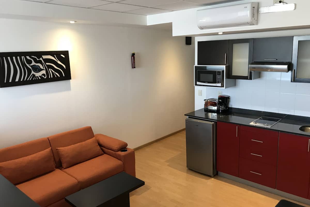 A modern kitchen with a microwave, toaster, and coffee maker. There is a red cabinet and a black countertop.