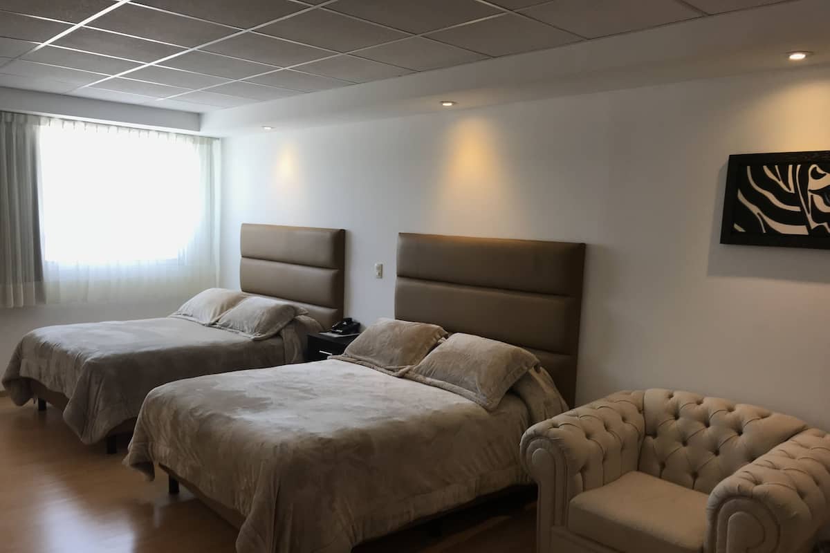 A hotel room with two beds, a chair, and a painting on the wall.