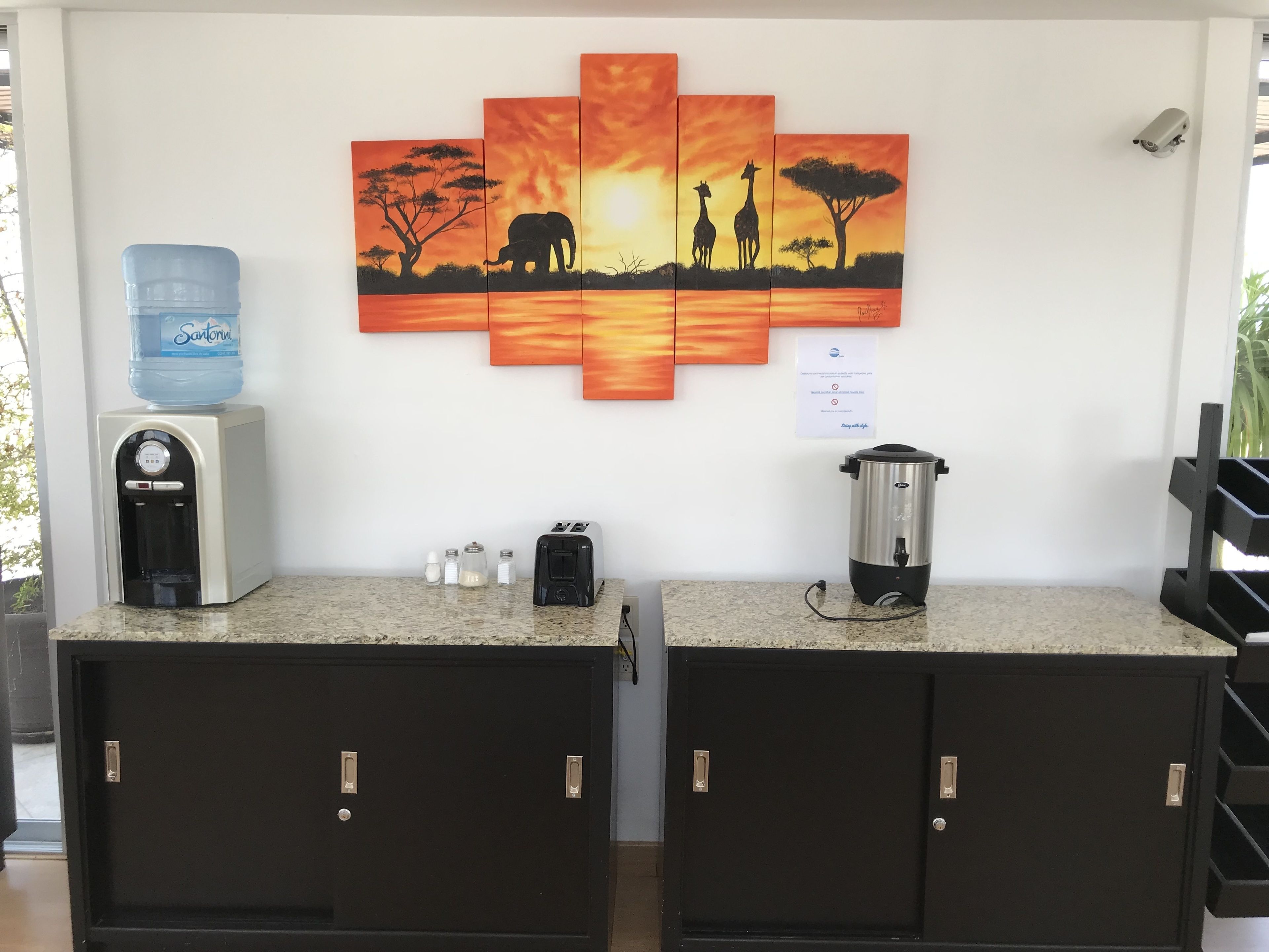 Una kitchenette con dispensador de agua, saleros y pimenteros, tostadora y cafetera.
