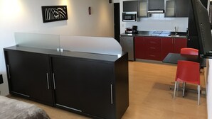 A modern kitchen with a black island, red cabinets, and a microwave. - My Home Suites (Celaya)