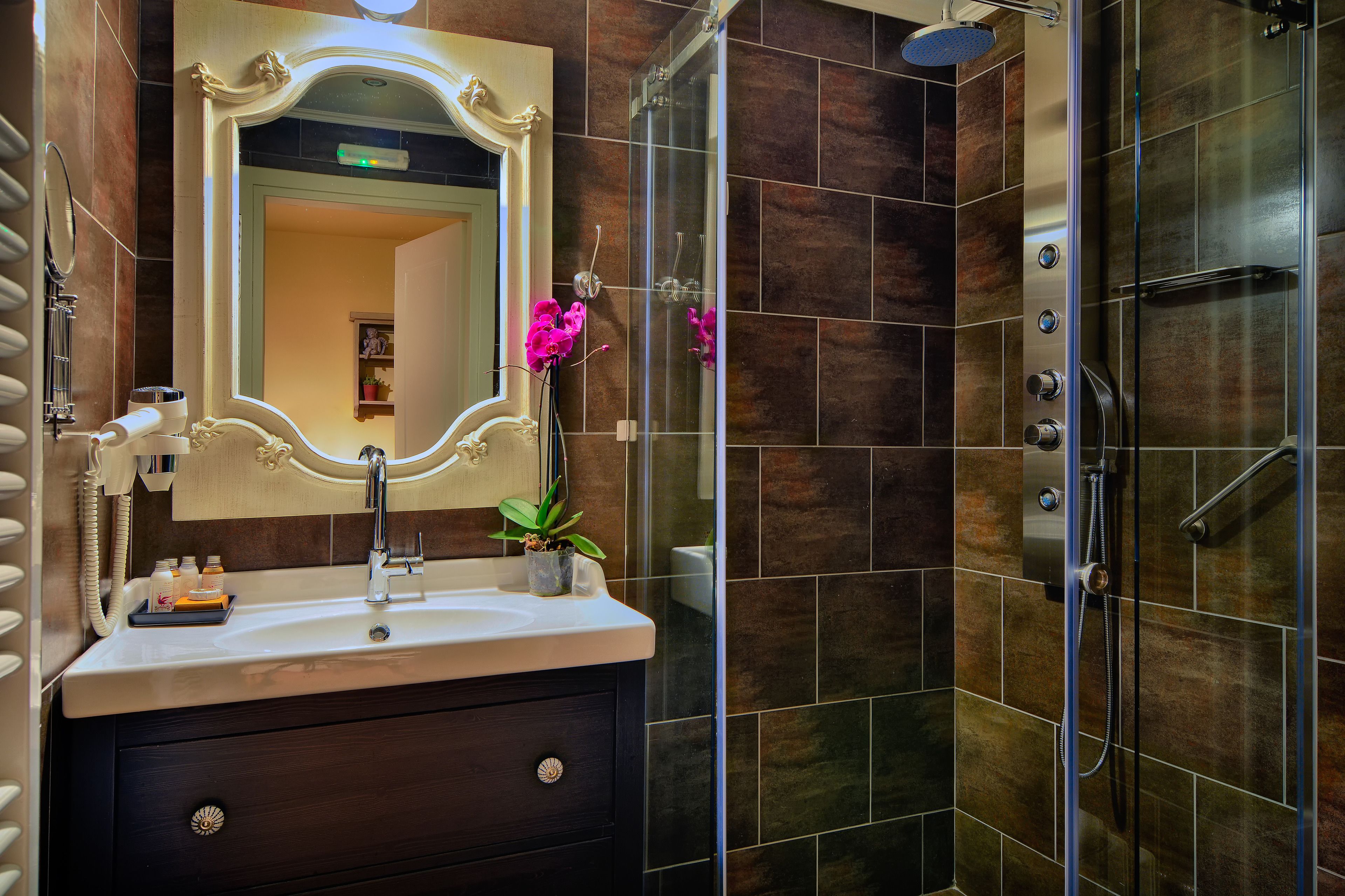 A modern bathroom with a large mirror, a sink, and a shower area.