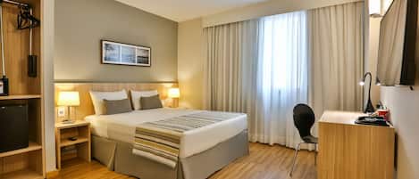 Una habitación de hotel con cama, lámparas de noche, escritorio y silla.