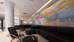 A modern waiting area with a long bench, cushioned chairs, and a colorful mural on the wall. - Days Inn Rio de Janeiro, Lapa (Rio de Janeiro)